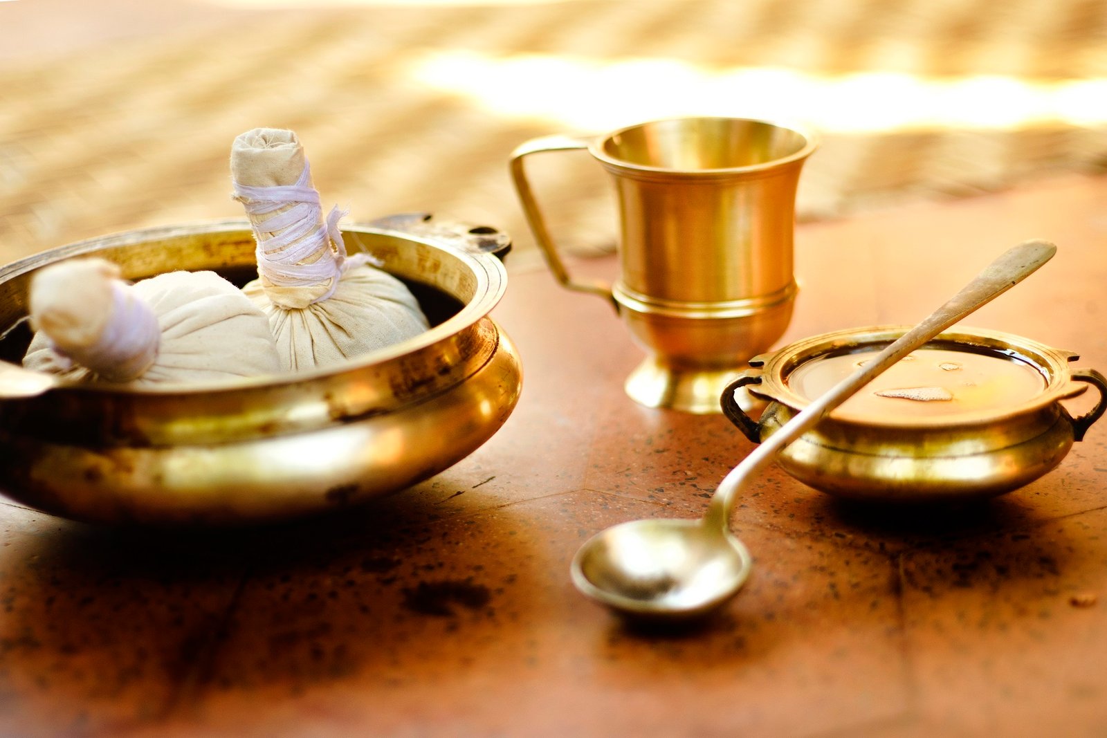 Brass Ayurvedic vessels and bundles of herbs laid out for a preparation