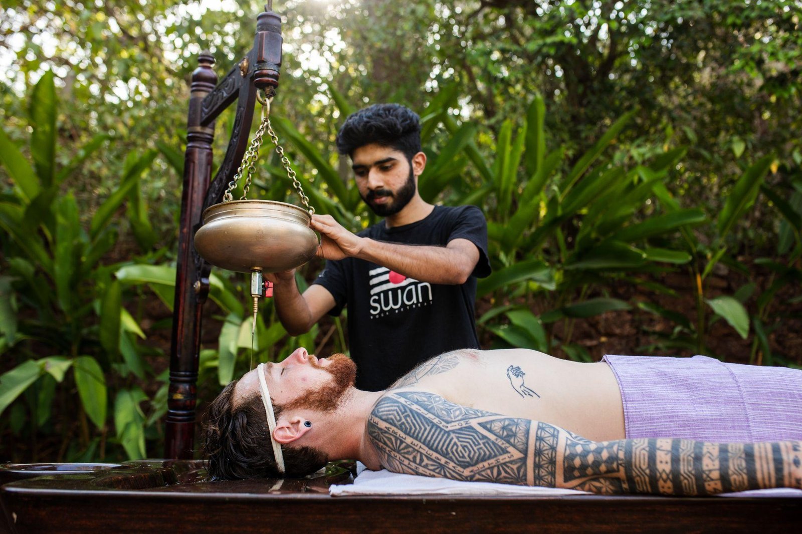Shirodhara — warm oil poured from a brass vessel onto the forehead, at SWAN Ayurveda